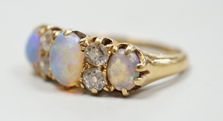 A late Victorian 18ct gold, three stone white opal and four stone diamond set half hoop ring, size M, gross weight 4.2 grams.